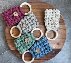 four crocheted baby toys are on a wooden board with buttons and handles in different colors