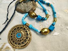 Be unique! Each jewel exists in only one copy and you will be the only one to wear it.  A mid-length necklace, ethnic rustic style: superb pendant of Indian origin! Beautiful and large brass beads that blend perfectly with the blue of the glass beads.  The pendant: 2,4' in diameter in old gold metal and I added a small blue enamel cabochon.  the beads of the necklace:  - large oval brass beads (25 mm)  - large commercial beads in blue opaque glass (15 mm)  - textured blue opaque glass beads (10 Boho Necklaces, Style Rustique, Beaded Rings, Pretty Jewellery, Jewelry Creation, Boho Necklace, Blue Glass, Gold Pendant, My Jewellery