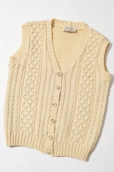 the sweater vest is knitted and has buttons on the front, along with an attached collar