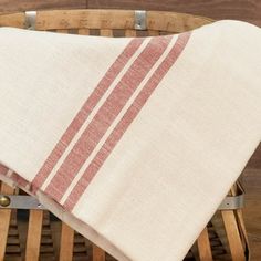 a white and red towel sitting on top of a wooden chair next to a basket