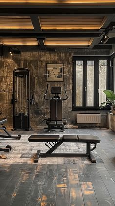 an empty gym with benches and exercise equipment in the foreground, large windows on either side