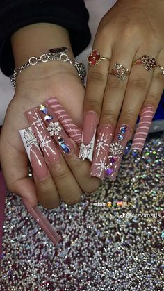 two hands with pink and white manies holding each other's nails in front of glitter