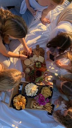 several people are gathered around a table with food on it