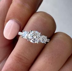 a woman's hand holding a three stone ring