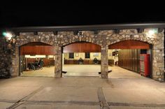 an empty parking lot with two garages and lights on at the end of it