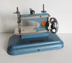 an old sewing machine sitting on top of a blue stand next to a white wall