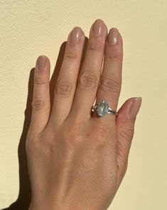 a woman's hand with a diamond ring on her left hand, in front of a white wall