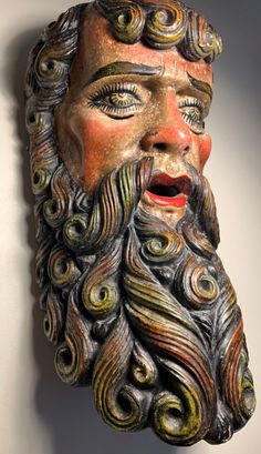 a sculpture of a man's face with long hair and beard, made out of clay