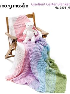 a white teddy bear sitting on top of a blanket next to a wooden lawn chair