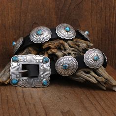 Sterling silver and turquoise concho belt. The rectangular buckle is 2 5/8" wide by 2 1/16" tall. There is a turquoise stone in each corner of the buckle. The buckle stones are approximately 11mm x 9mm. The back is stamped STERLING and MR, the hallmark of Paiute artist Michael R. Rogers. There are 11 oval conchos. Each has a turquoise stone in the center and measures 1 3/8" by 1 3/16". The concho stones are approximately 9mm long x 6mm wide. The belt has been put onto a new dark brown leather st Southwestern Turquoise Concho Belt Buckles, Western Turquoise Belt With Concho, Turquoise Western Belt With Concho, Blue Concho Western Belt Buckles, Western Style Blue Concho Belt Buckles, Silver Southwestern Concho Belt, Southwestern Silver Concho Belt, Turquoise Bohemian Belt With Concho, Concho Belt