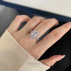 a woman's hand with a diamond ring on top of her finger and an oval shaped diamond in the middle