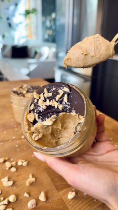 a hand holding a spoon full of peanut butter and chocolate covered cookie in a jar