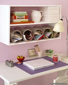 some books and magazines are sitting on a shelf in the corner next to a lamp