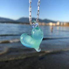 "One of a kind ocean inspired borosilicate glass heart necklace in Aqua Zen - a gorgeous ocean Inspired light turquoise iridescent blue. Perfect for the ocean and beach lover. Minimalist design that is great for any occasion.  Approximately 1\" x 1\" Pendant comes with black paracord or sterling silver stamped 925, 1 mm ball, snake or 2mm Sterling Silver paperclip chain.  Select your length at check out.  All chains are made in Italy.  Each piece is completely handmade and is one of a kind. Therefore, sizes are approximate and design is unique and may vary slightly from the images. Thanks for shopping small! Hand made in Vancouver, BC, Canada" Light Blue Heart Beads Jewelry Gift, Light Blue Heart Beads Jewelry For Gift, Light Blue Heart-shaped Jewelry Gift, Light Blue Glass Jewelry For Gifting, Light Blue Glass Jewelry For Gifts, Light Blue Glass Jewelry Gift, Clear Glass Heart-shaped Jewelry, Heady Glass, Iridescent Blue