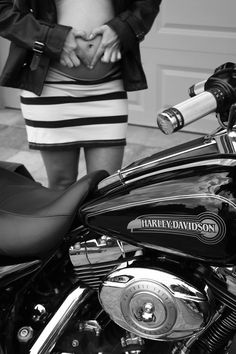 a woman standing next to a motorcycle with her hand on the handlebars and wearing a skirt