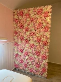 there is a toilet in front of a wall with pink and white flowers on it