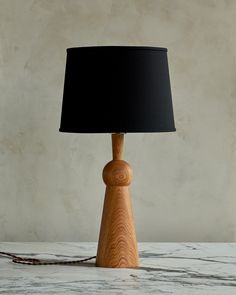 a wooden table lamp sitting on top of a white marble counter next to a black lampshade