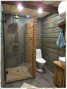 a bathroom with a toilet, sink and shower in it's stall area next to a wood paneled wall