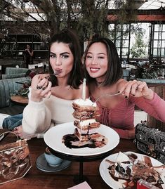 two women sitting at a table eating desserts