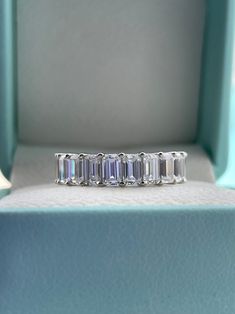 an emerald cut diamond ring sits in a box