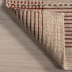 a close up of a rug on a wooden floor with a white and red striped design