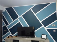 a flat screen tv sitting on top of a wooden cabinet in front of a blue wall