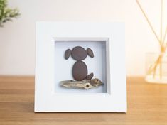 a small white frame with a brown dog in it on a wooden table next to a potted plant