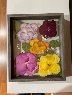 a person standing next to a box with fake flowers in it on top of a wooden floor