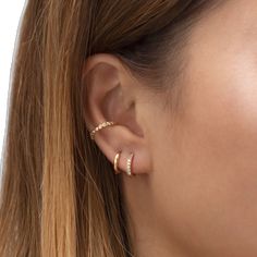 a close up of a woman's ear with two small gold hoops on it