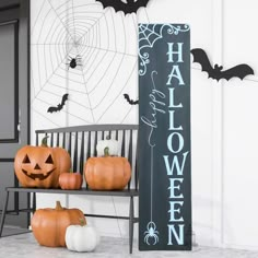 two pumpkins sitting on a bench in front of a halloween sign