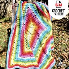 a crocheted blanket sitting on top of a chair in front of a tree