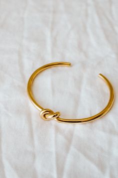 Our Knot Bangle is timeless and elegant. It can be worn by itself or as a layering piece with your watch. PRODUCT DETAILS 18k Gold plated stainless steel polished Nickel free SIZING & MEASUREMENT5.8cm inner diameter, 3.2mm thickness CARE For the longest shine avoid contact with water, perfume, moisturizer and hairspray. We recommend you remove your jewelry when showering, exercising, at the beach, or swimming in chlorinated water. All pieces featuring pearls and natural gemstones are very precio Timeless Gold Plated Cuff Bracelet As Gift, Adjustable Gold-plated Bangle With Polished Finish, Gold-tone Polished Bangle As A Gift, Adjustable Gold Stainless Steel Cuff Bracelet, Gold-tone Polished Bangle Perfect For Gifts, Gold-tone Polished Finish Bangle For Gift, Adjustable Gold Timeless Bangle, Gold Adjustable Timeless Bangle, Classic Gold-tone Bangle As Gift