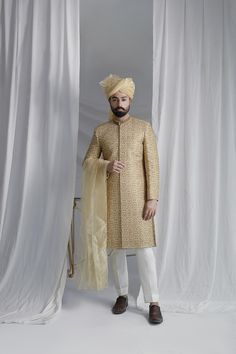 Discover the timeless elegance and regal charm of our Collar Detail Gold Sherwani. Made from pure atlas material, this sherwani features exquisite hand-embroidered jal work of resham, zardozi, Swarovski stones, and dabka. Complete with a jamawar kula (turban) and silk inner kurta pajama, this resplendent piece is perfect for any special occasion. Elevate your style with this luxurious and sophisticated sherwani. 4-Piece Suit Gold Sherwani With Dupatta In Raw Silk, Gold Sherwani With Intricate Embroidery In Raw Silk, Ceremonial Raw Silk Sherwani With Naqshi, Gold Sherwani With Resham Embroidery And Kundan, Ceremonial Naqshi Sherwani In Raw Silk, Gold Traditional Wear With Naqshi Drape, Traditional Gold Unstitched Suit With Naqshi Detailing, Traditional Gold Unstitched Suit With Naqshi, Festive Gold Sherwani With Naqshi Detailing