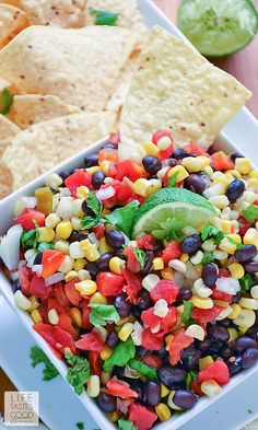 a bowl filled with black beans, corn and guacamole next to tortilla chips