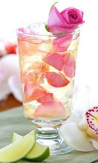 a glass filled with ice and pink flowers on top of a table next to cookies