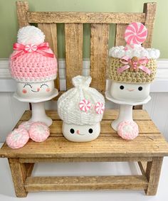 three knitted items sitting on top of a wooden bench