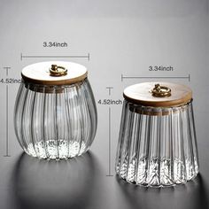 two clear glass jars with wooden lids are shown next to each other on a table