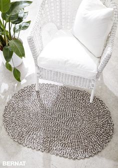 a white chair sitting on top of a rug next to a potted plant