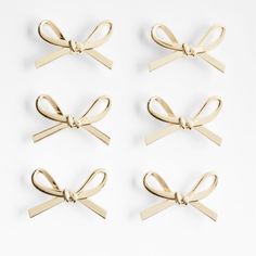 four pairs of gold bow clips on white background