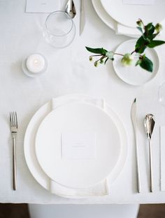 the table is set with white plates and silverware