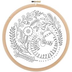 an embroidery pattern with flowers and leaves in the center on a wooden hoop hanging from a hook