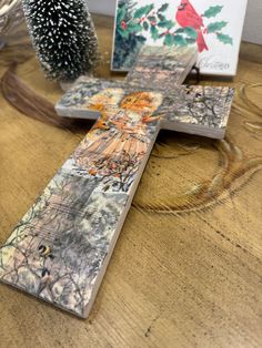 a wooden cross sitting on top of a table next to a christmas tree and greeting cards