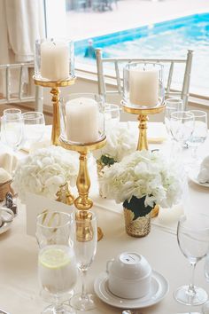 the table is set with white flowers and gold candlesticks for an elegant centerpiece