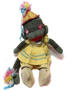 a stuffed animal wearing a yellow dress and a knitted hat with pom poms