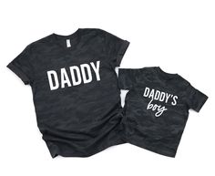 Daddy /daddy's boy matching tees Adult Sizing: We recommend going up in size for men who are in-between sizes or who enjoy a relax fit. For women, we recommend going down a size to get a more true to size fit. We recommend going up in size for men who are in-between sizes or who enjoy a relax fit. Prints: All of our full color graphics tees are made with screen print inks giving shirts excellent vibrancy, touch, and durability. Our one-two color graphics are made of soft touch vinyl which provid Family Matching T-shirt For Father's Day, Matching Family T-shirts For Father's Day, Father's Day Matching Family Shirts, Family Matching Shirt With Name Print For Father's Day, Father's Day Matching Black T-shirt, Black T-shirt For Father's Day, Black T-shirt For Father's Day Parenting, Father's Day Matching Letter Print Shirt, Black Shirt For Father's Day