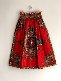 "Red Dashiki high waist full gathered skirt. Perfect for casual outfits and special occasions with pair of trainters or high heels. 100% cotton.  Elastic at the back of waist.  Two side pockets. Midi length about 76cm + 5 cm waistband. Handmade in UK.  HOW TO CHOOSE A SIZE ?   Using a measuring tape, measure the smallest part of your waist.  SIZE CHART: (CM) XS - W: 66 CM S - W: 70 CM M - W: 74 CM  L - W: 78 CM  XL - W: 82 CM  CARE INSTRUCTIONS: Hand wash only, do not bleach, hang dry, do not tumble dry, press with a cool iron on the reverse side.  Please message me before purchasing so I can check availability. If you wish this skirt in any other fabric, shorter or longer \"send message to seller\" and we can try to make something especially for you. *Depends on computer/monitor settings Red Midi Skirt With Elastic Waistband, Red Cotton Flared Skirt Bottoms, Red Cotton Midi Skirt, Traditional Red Bottoms For Summer, Red Cotton Long Skirt, Red Cotton Lined Skirt, Bohemian Red Full Skirt, Red Cotton Flared Skirt, Red Full Skirt With Elastic Waistband