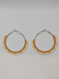 60 mm hoop earrings beaded by hand featuring daffodil yellow, cream white, and orange glass seed beads. Orange Hoop Earrings With Colorful Beads, Bohemian White Beaded Hoop Earrings, Handmade Orange Hoop Earrings, Orange Beaded Hoop Earrings, White Hoop Earrings With Tiny Beads, Adjustable White Hoop Earrings With Colorful Beads, Bohemian Yellow Hoop Earrings, White Bohemian Small Hoop Beaded Earrings, White Tiny Beads Small Hoop Earrings