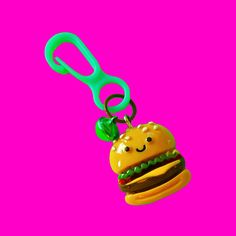 a hamburger with a pair of scissors hanging from it's side on a pink background