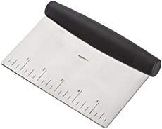 a large metal cutting board with a black handle and ruler on the bottom, in front of a white background