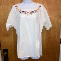 a white shirt with flowers on it is hanging from a wooden door frame in front of a wood paneled wall